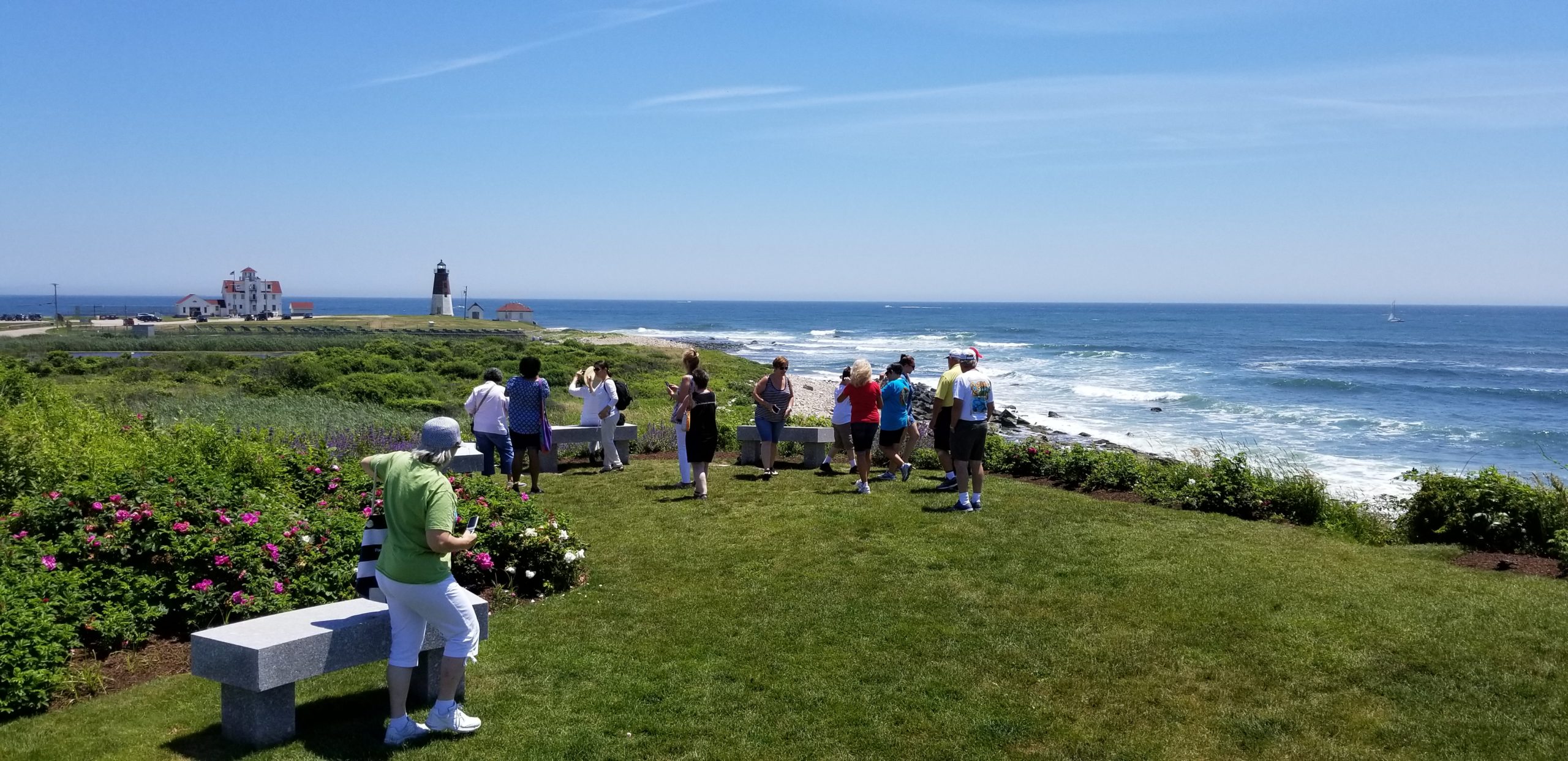 Group picture of tourists with the view of Point Judith Lighthouse - an experience included in the Scenic Rhode Island Tour.