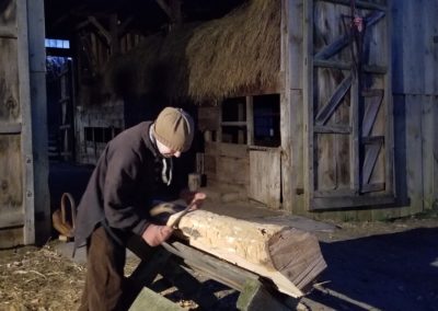 A worker carving wood at night - a view included in Christmas by Candlelight at Old Sturbridge Village Tour.