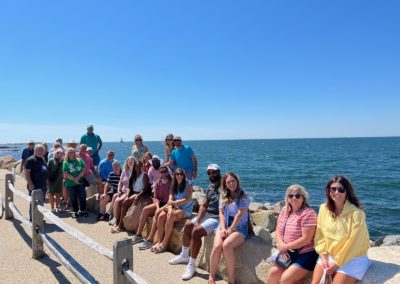 Group picture of tourists at Breakwater Point in Little Compton, RI - included in the Come Away to the Quiet Coast Tour.