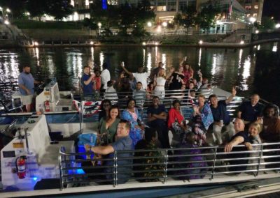 Group picture of tourists waving while on a boat tour by the Providence River taken during the Dinner and a Cruise Tour.