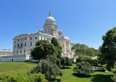 Side View of the Rhode Island State House with tall green trees surrounding it - included in the Discover Providence Tour.