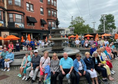 Group picture of tourists sitting around the DePasquale Fountain in Providence, RI taken during The Italian Experience Tour.