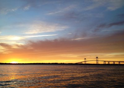 Spectacular view of a sunset sky behind Newport Bridge - an experience included in The Coast Guard House & Sunset Sail Tour.